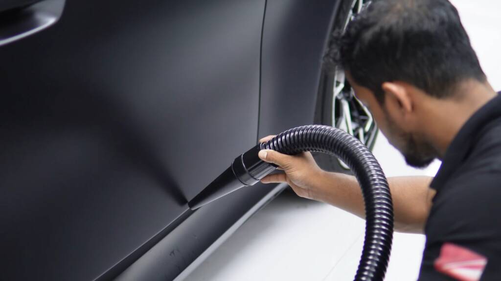 Apex installer using an air blower on a BMW M5 Touring panel during matte PPF installation