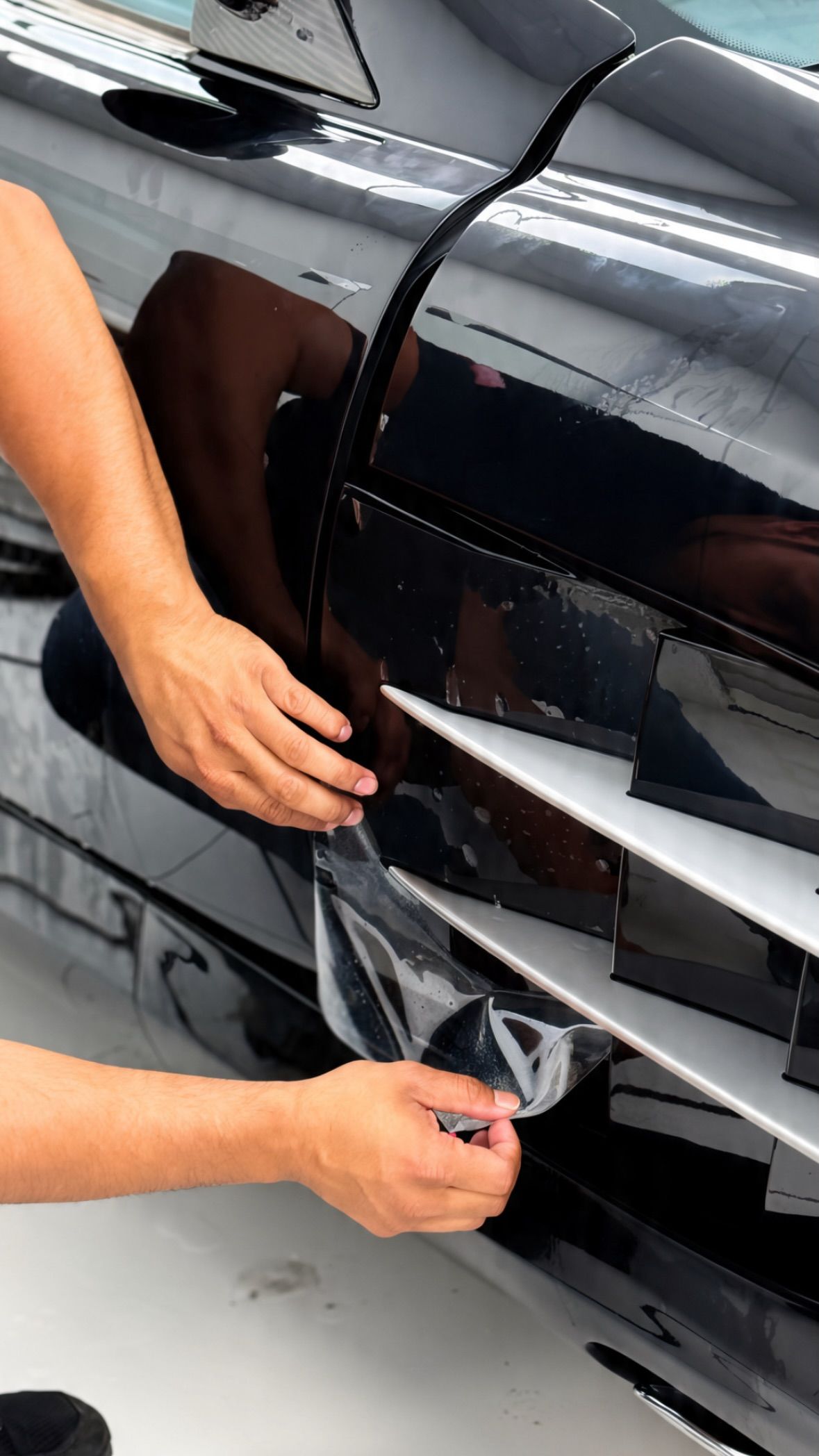 Installer finishing PPF on a black car door at Apex Detail Studio Dubai