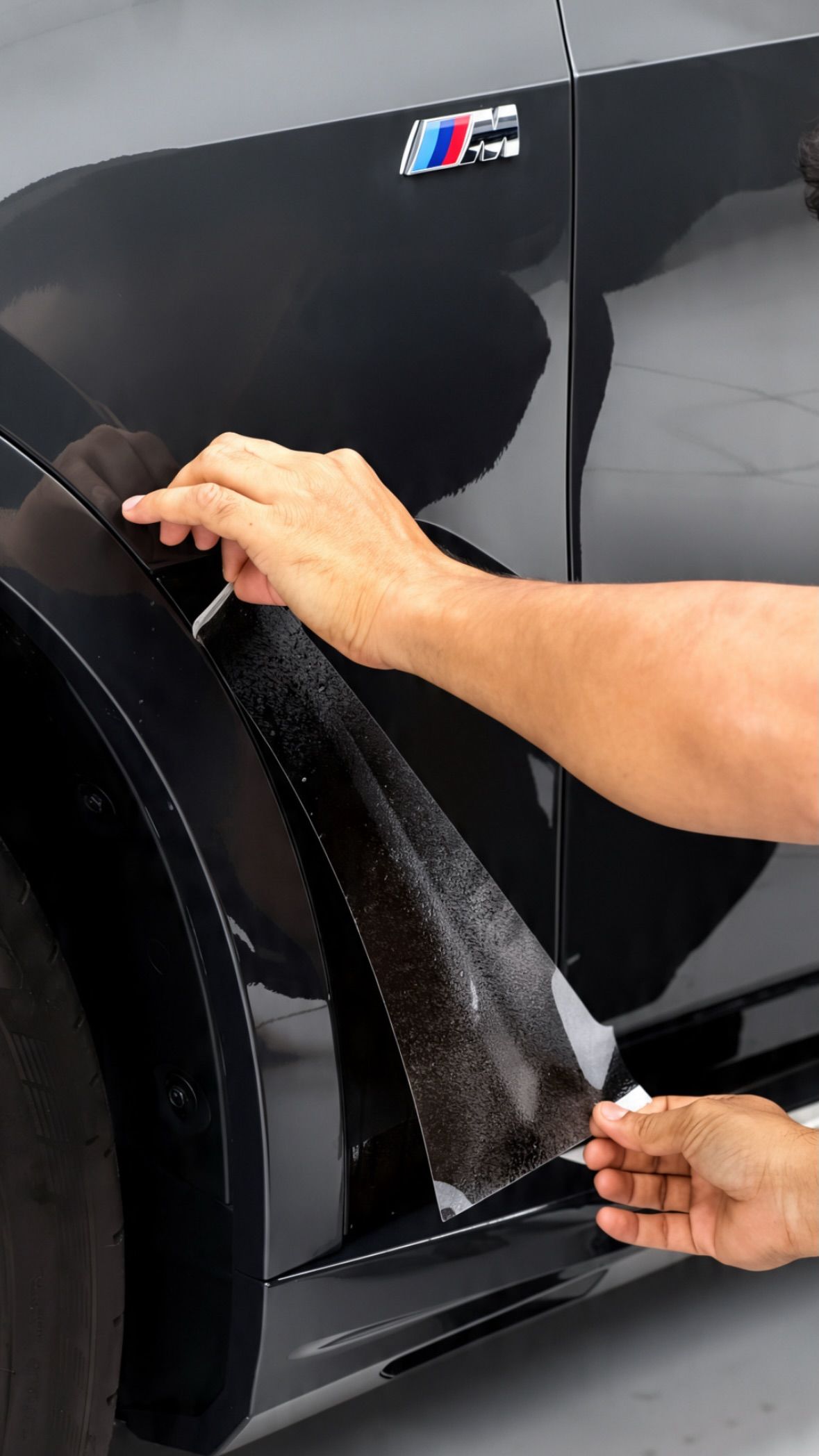 Installer applying PPF to a black BMW door at Apex Detail Studio Dubai