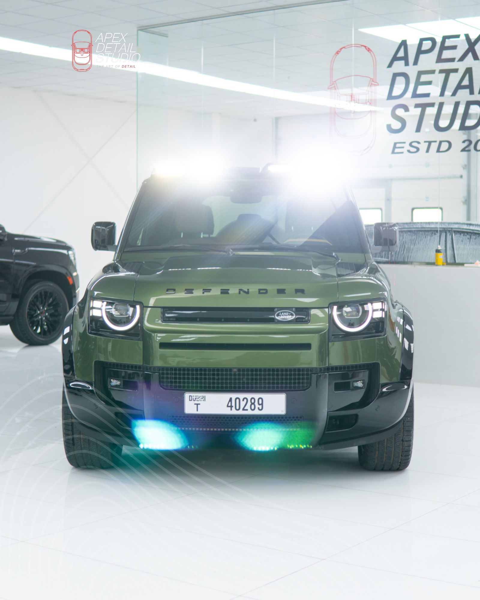 Green Land Rover Defender with headlights on inside Apex Detail Studio Dubai