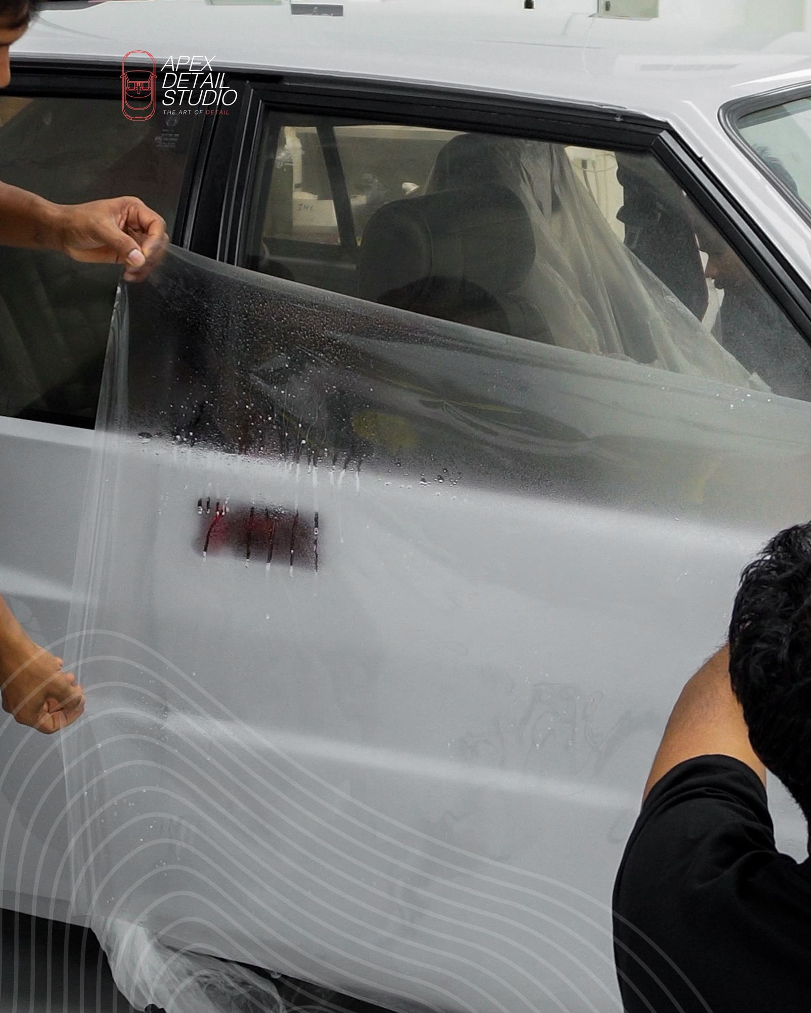 Installer fitting paint protection film to a grey car door at Apex Detail Studio Dubai