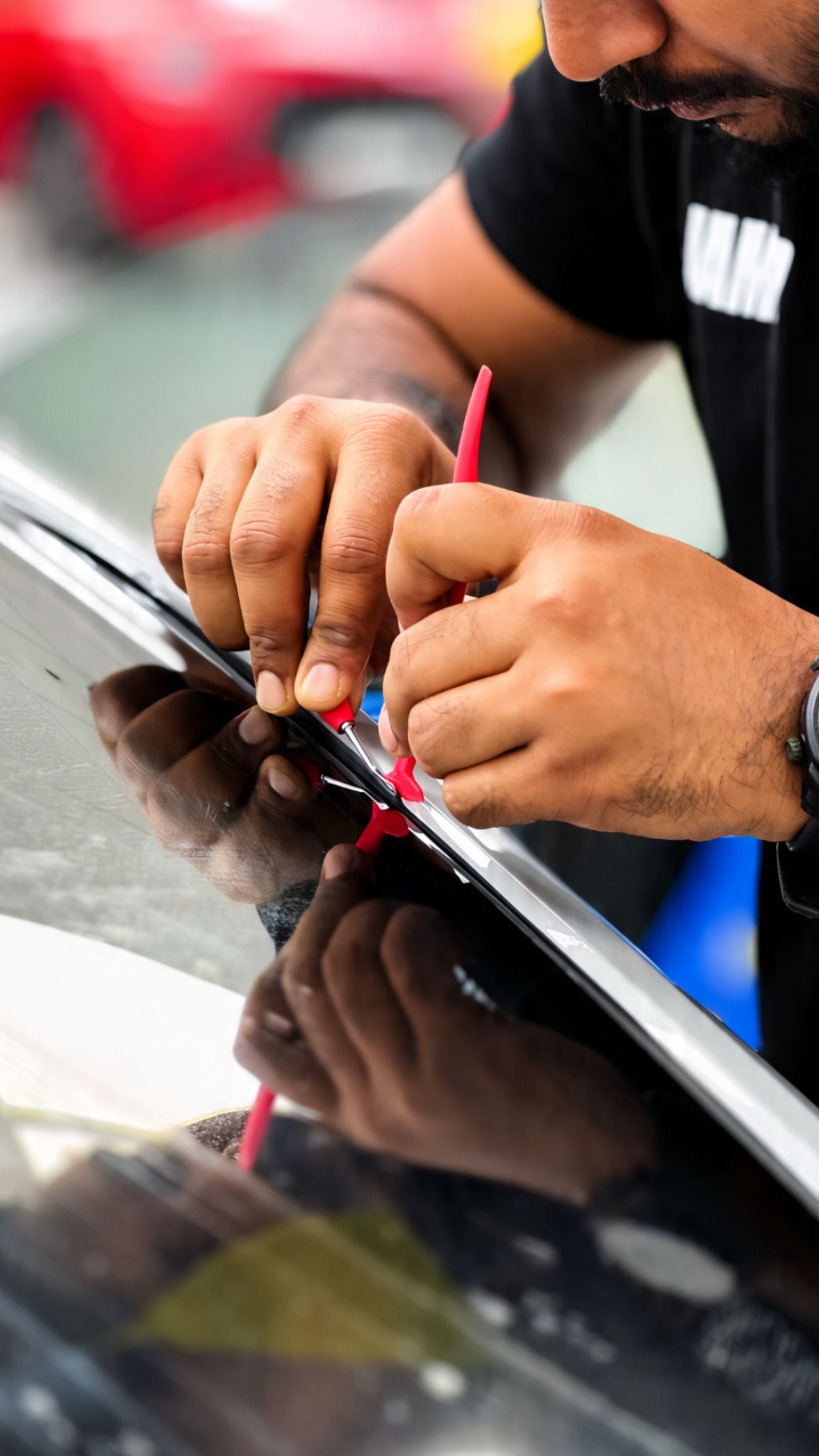 Installer trimming paint protection film along the edge of a black car panel at Apex Detail Studio Dubai