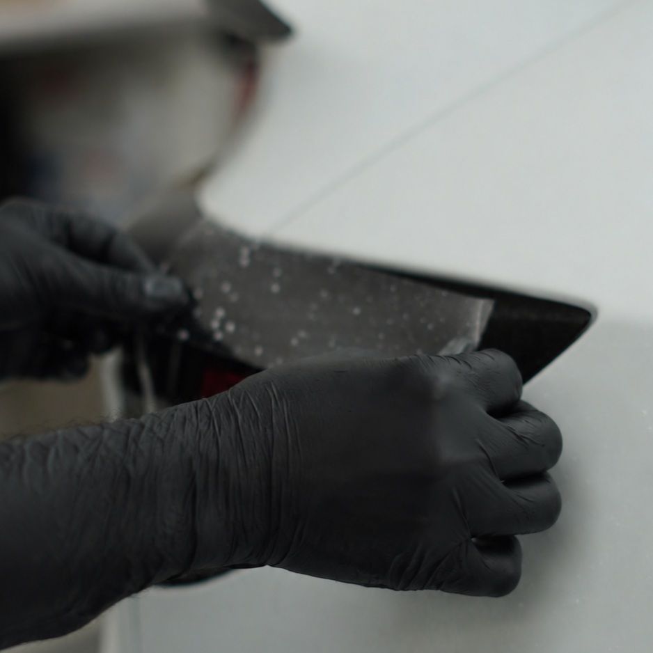 Gloved hands trimming paint protection film at Apex Detail Studio Dubai