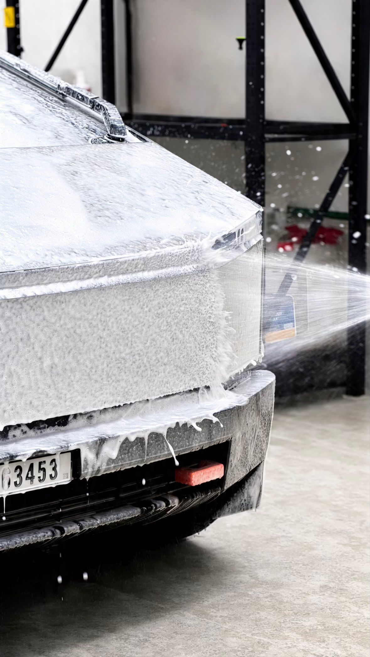 Car covered in snow foam during a wash at the Apex studio