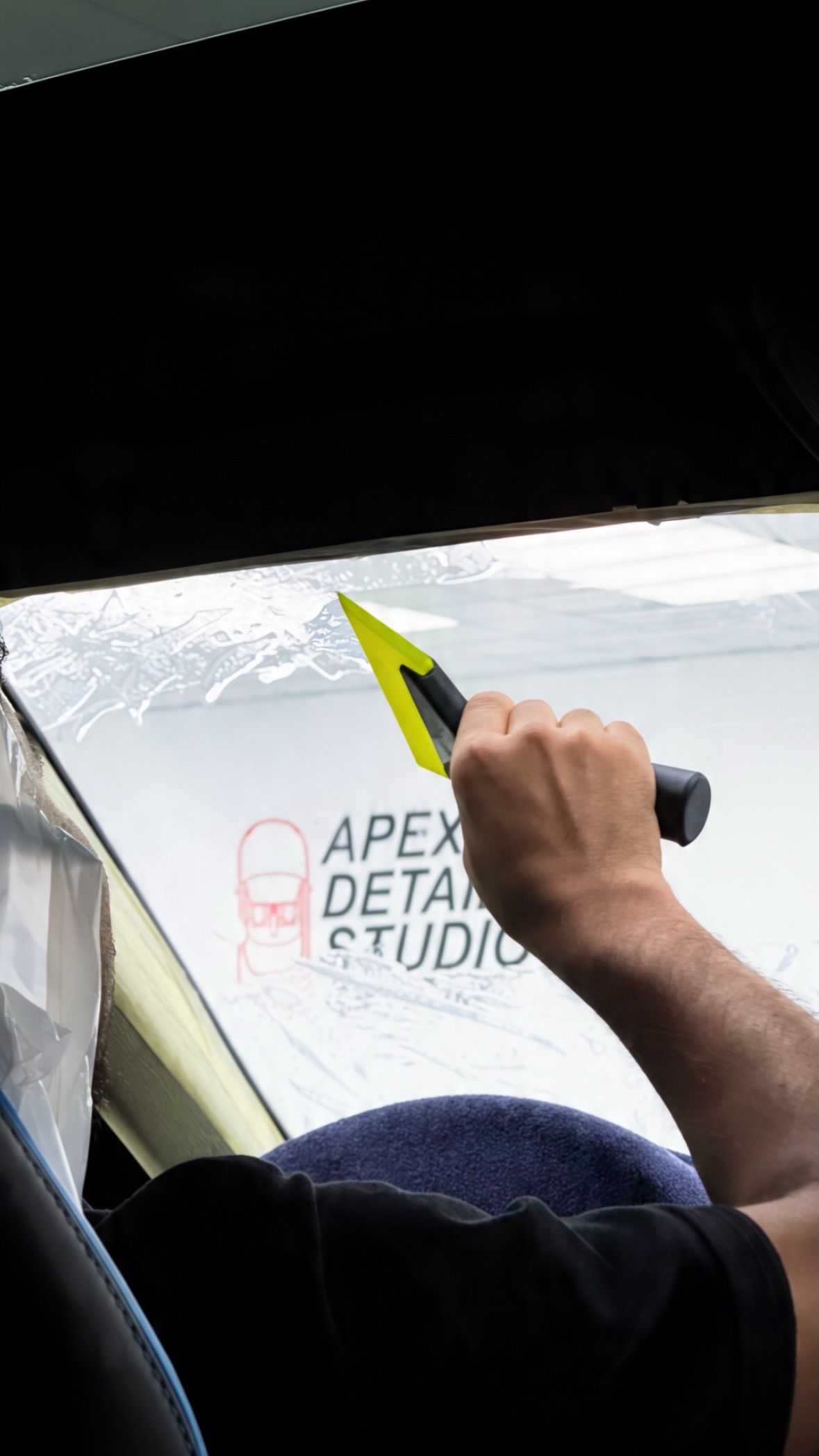 Window tint being applied from inside a car at Apex Detail Studio