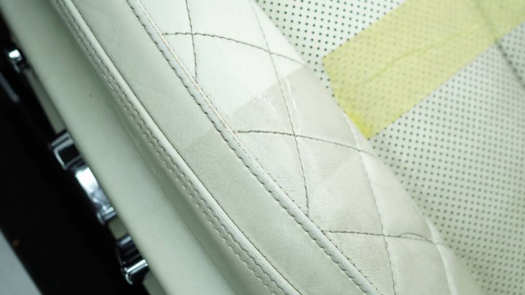 Masked test section on a Bentley seat during cleaning