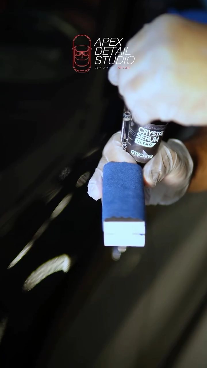 Gloved hand holding a ceramic coating applicator for the black BMW at Apex Detail Studio Dubai