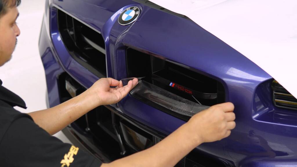Installer fitting PPF around the kidney grille of a BMW M2 CS