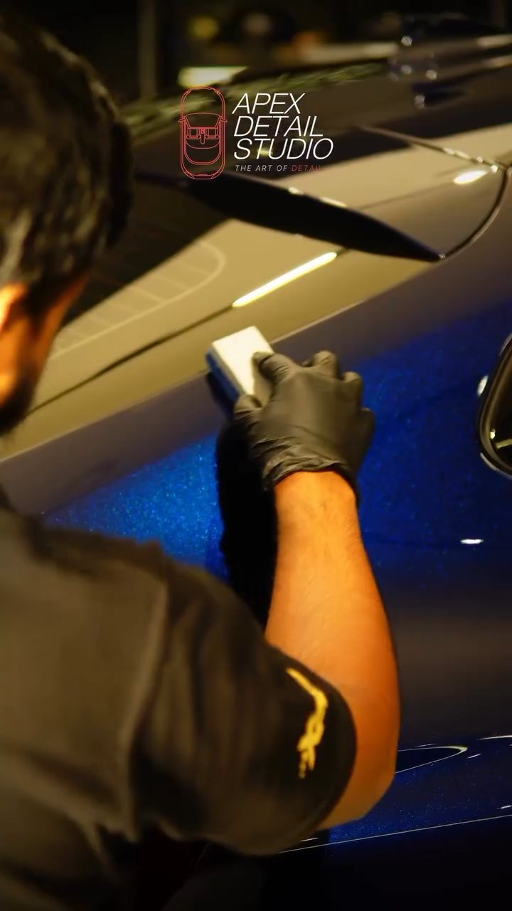 Detailer applying ceramic coating to the blue BMW X4 door in Dubai