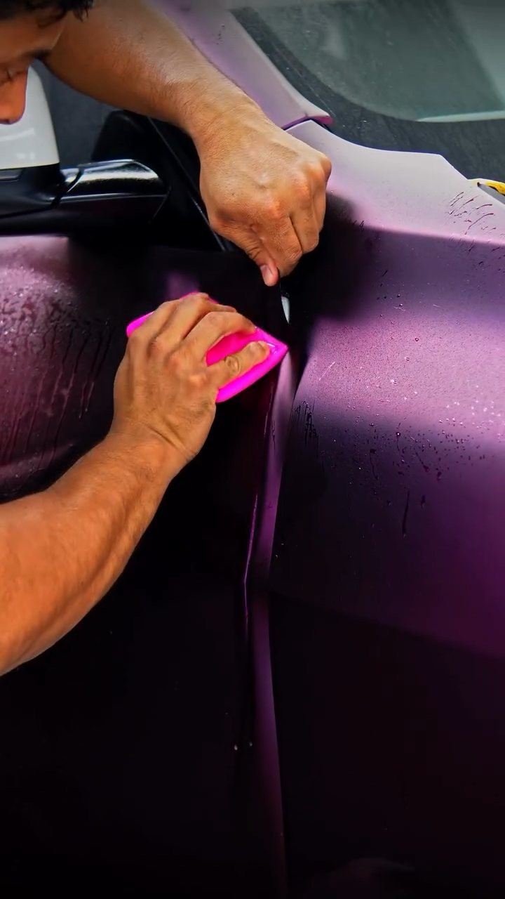 Squeegeeing purple colour PPF on the BMW X5 door at Apex Detail Studio Dubai
