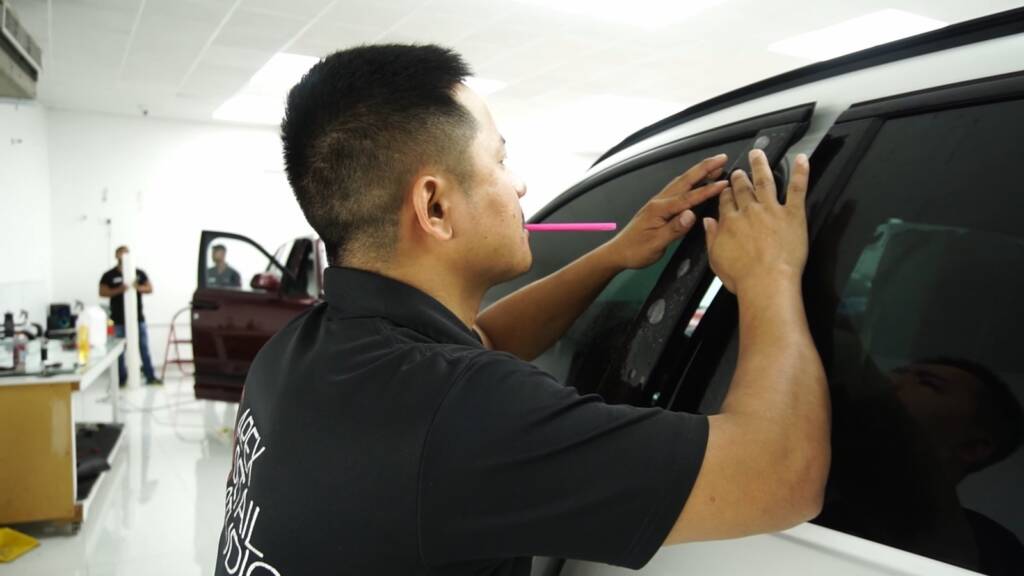 Installer fitting matte PPF along the 2024 BMW X6 M Competition door and window trim at Apex Detail Studio Dubai