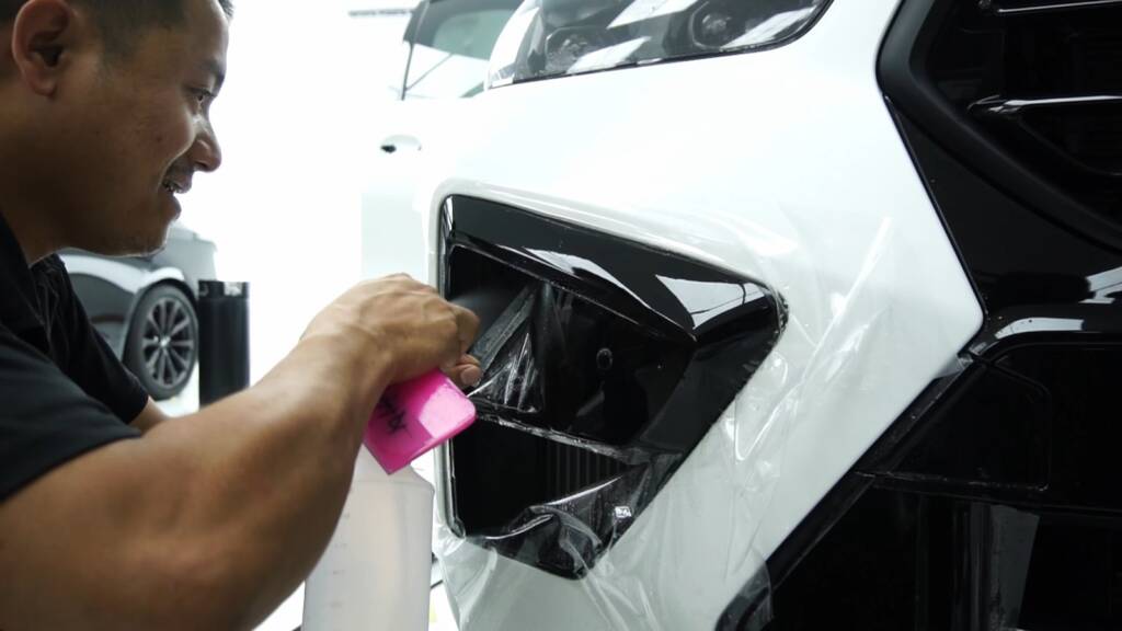 Installer squeegees premium satin PPF on the 2024 BMW X6 M Competition rear quarter at Apex Detail Studio Dubai