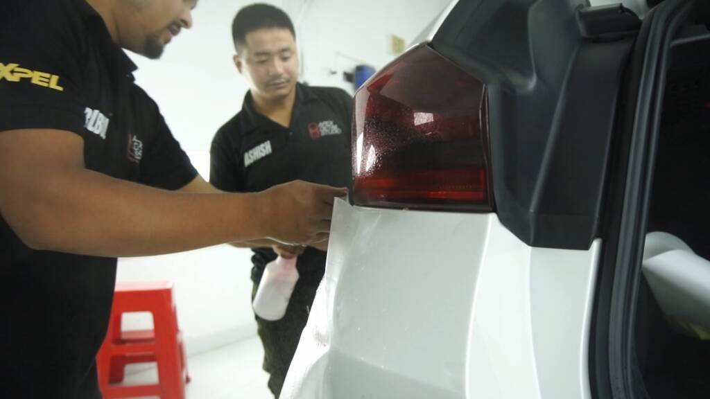 Installers wrapping PPF edges by the 2024 BMW X6 M Competition tail light at Apex Detail Studio Dubai