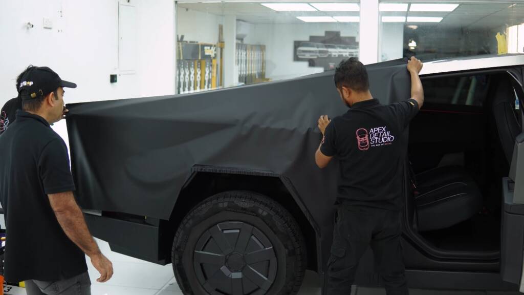Apex Detail Studio team laying a large sheet of PPF on a Tesla Cybertruck door