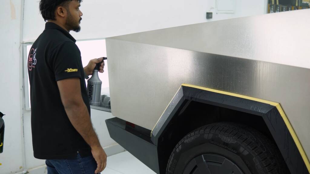 Checking a stainless steel Cybertruck panel under studio light before PPF