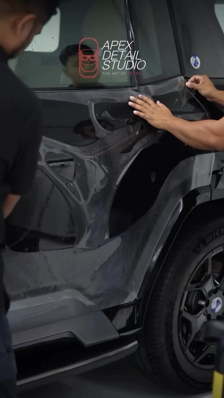 Installer preparing the black Denza B8 door for PPF at Apex Detail Studio Dubai