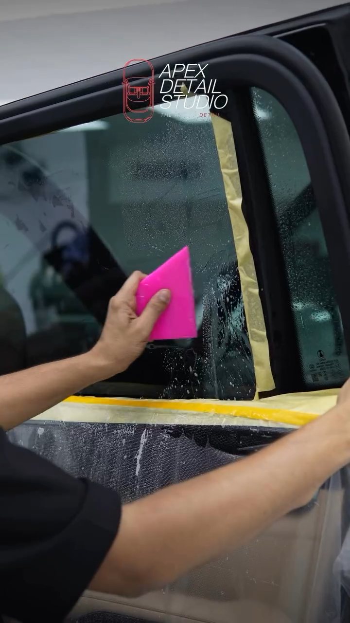 Window tint being squeegeed on the Denza B8 door glass at Apex Detail Studio
