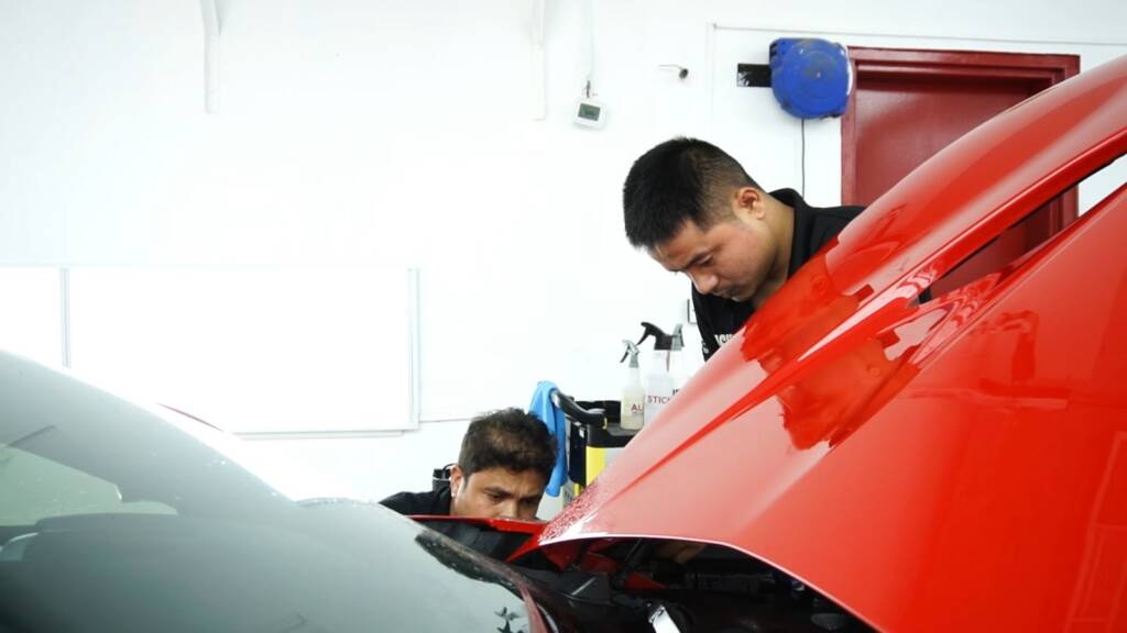 Installers fitting new PPF to a Ferrari Portofino wing