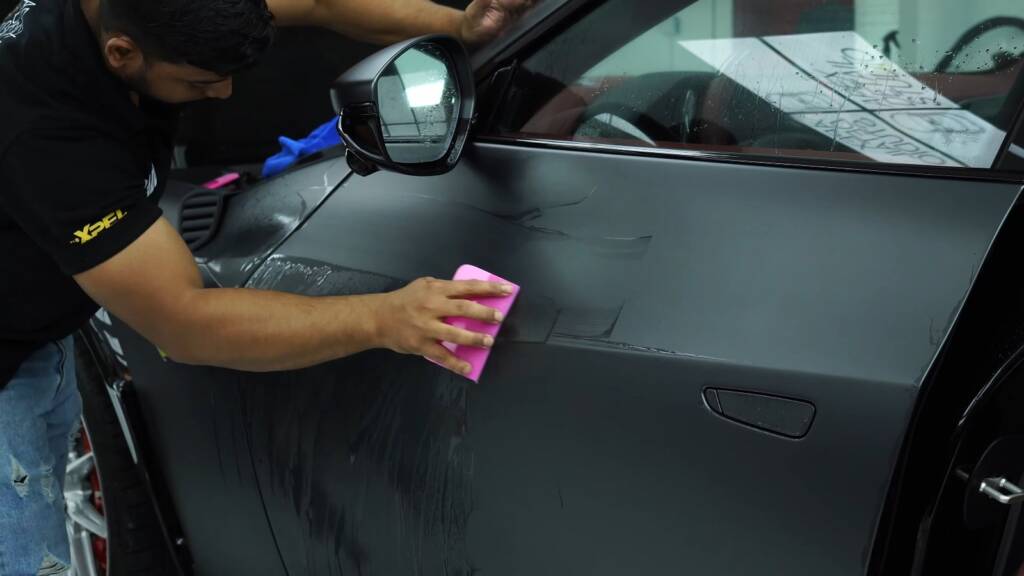 Installer setting satin PPF on a car door at Apex Detail Studio Dubai