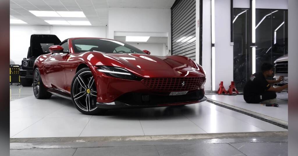 Installer finishing window tint on a red Ferrari Roma, Apex Dubai