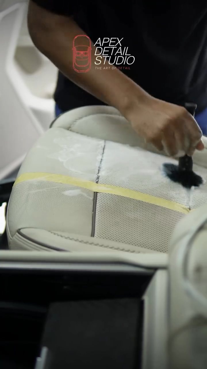 Detailer cleaning a taped test section on the GMC Denali leather seat at Apex Detail Studio Dubai