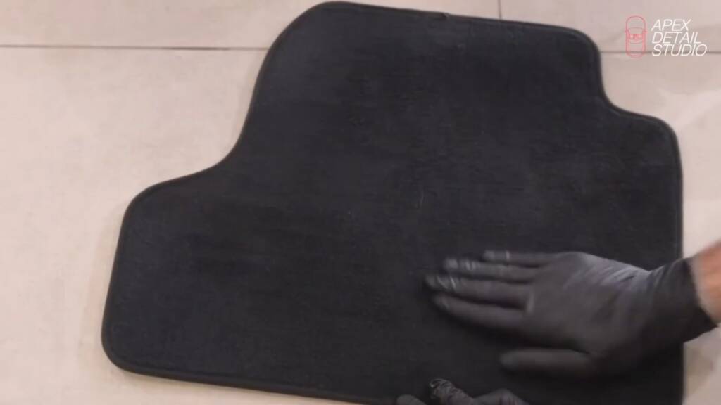 Gloved hand working Gtechniq Smart Fabric into car carpet at Apex Detail Studio