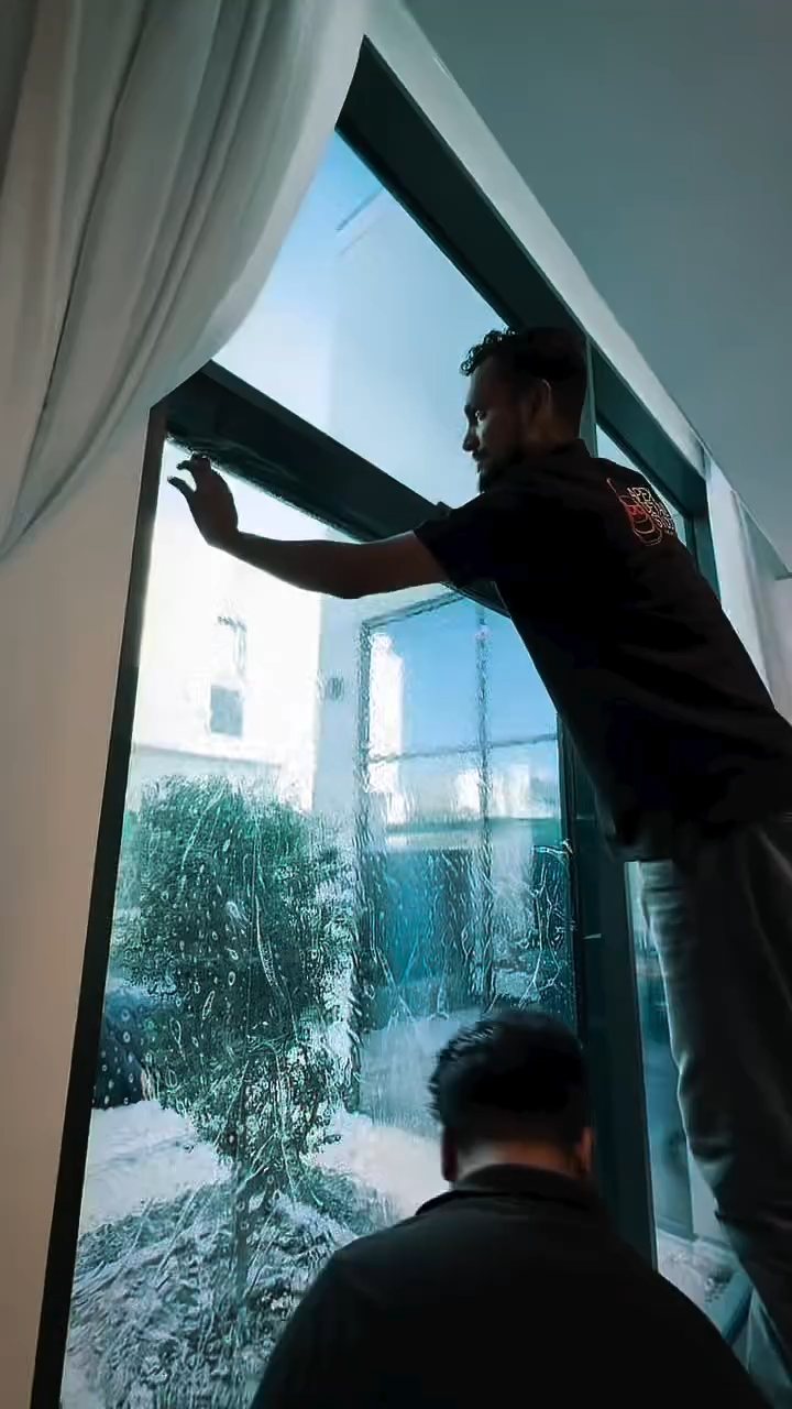 Installer fitting heat rejection film to a garden-facing window in a Dubai villa