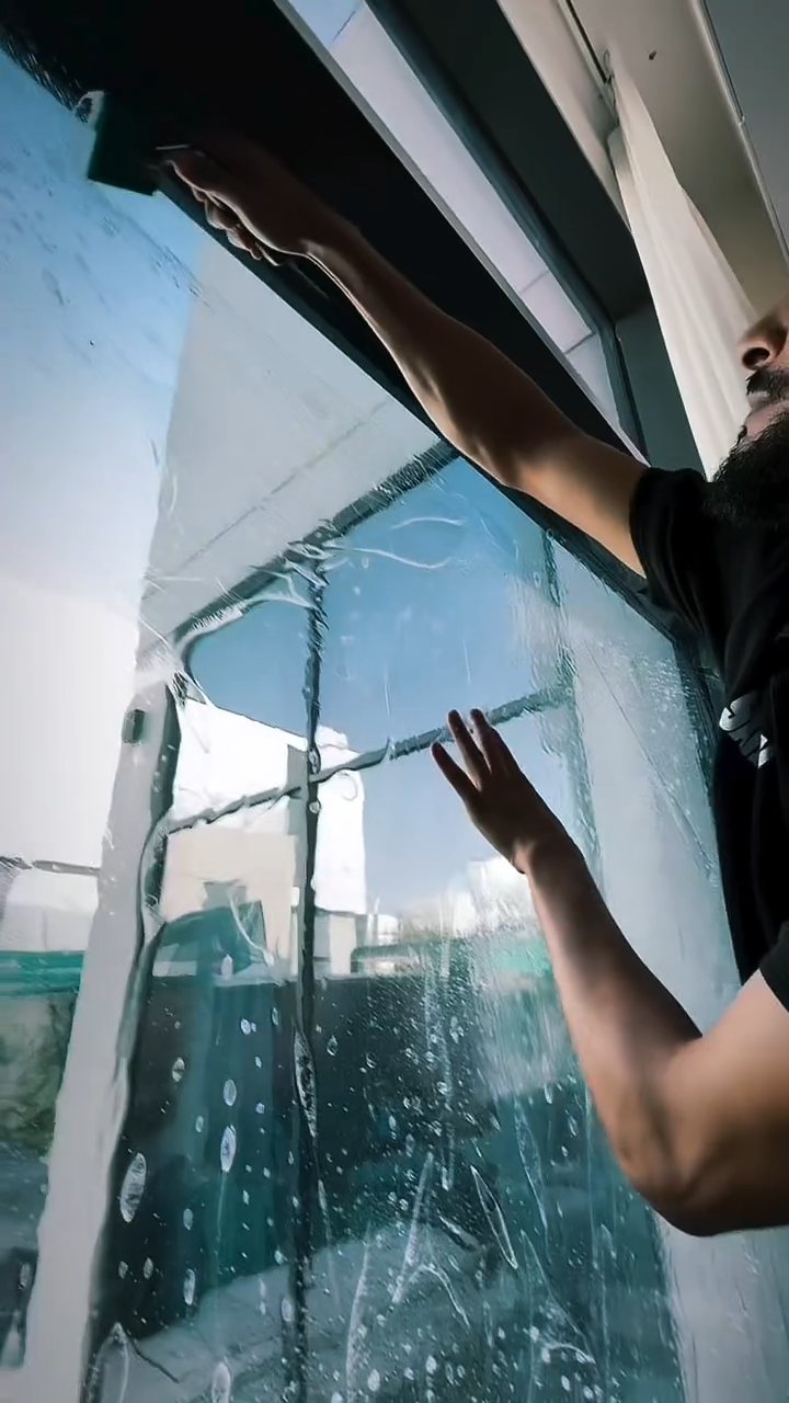 Installer squeegeeing home window tint film on glass at a Dubai villa