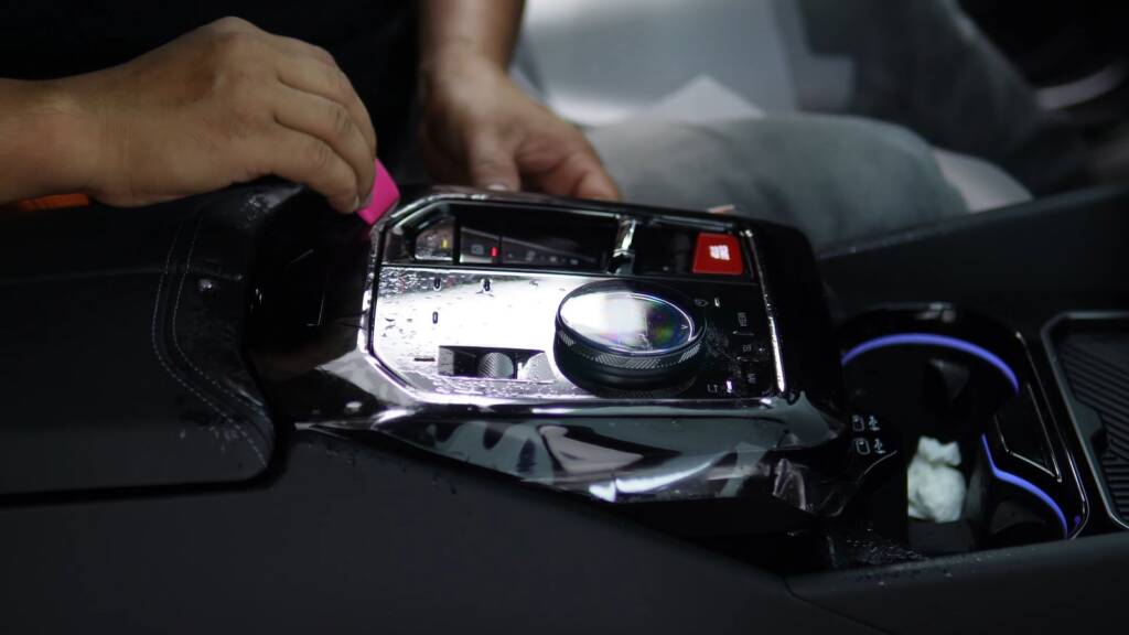 Clear PPF being fitted to the gloss black centre console of a BMW M5 Touring