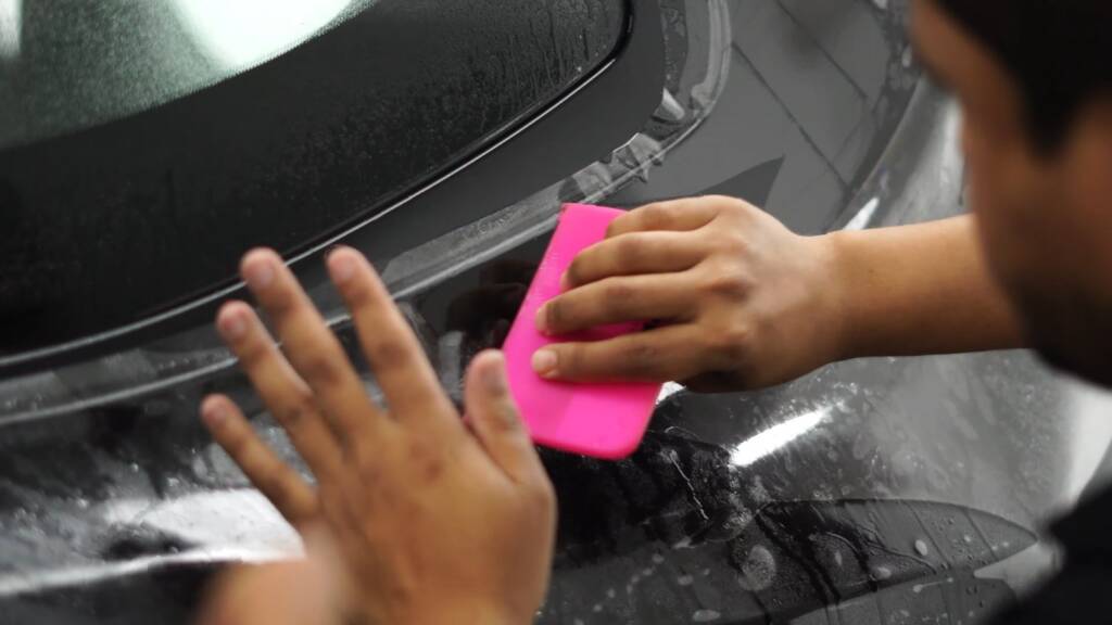 Jetour G700 headlight PPF being applied with squeegee at Apex Dubai