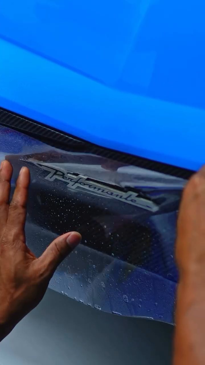 Hands fitting PPF on the blue Lamborghini Urus Performante lower door in Dubai