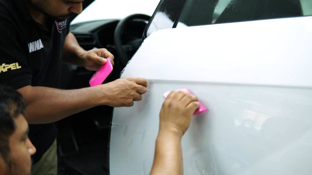 Two installers squeegeeing PPF on the door of a Lamborghini Urus SE