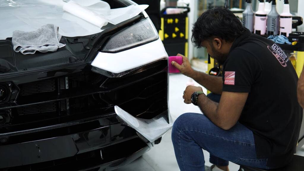 Installer fitting PPF on the front bumper of a Lamborghini Urus SE