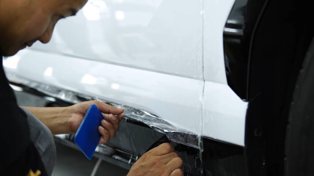 PPF being squeegeed on the side skirt of a white Lamborghini Urus SE