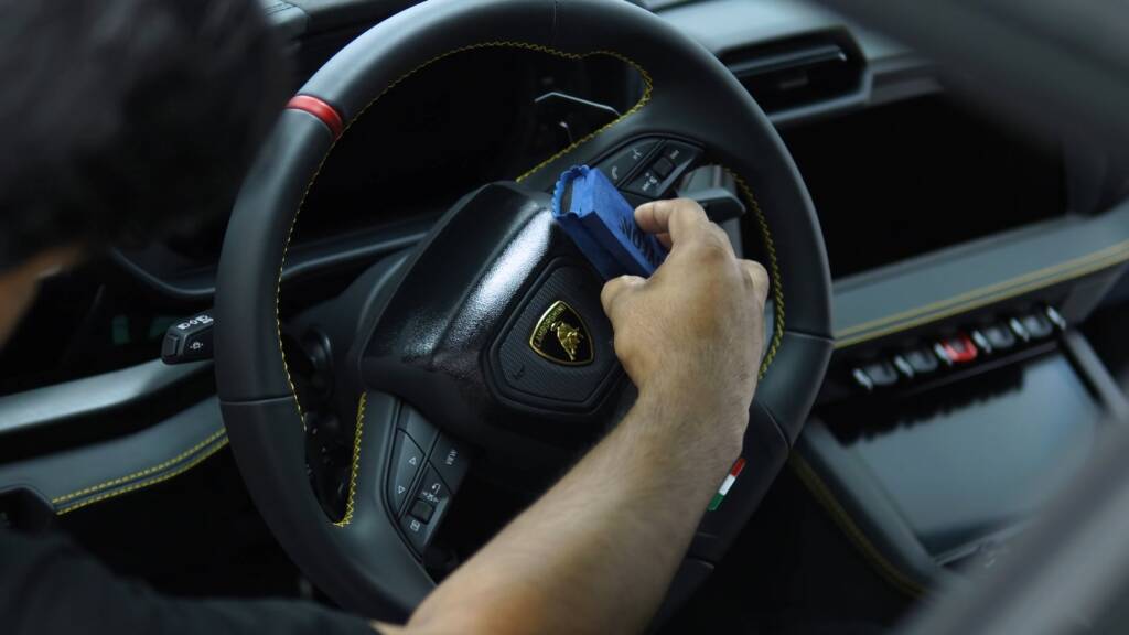 Detailer cleaning the steering wheel of a Lamborghini Urus SE
