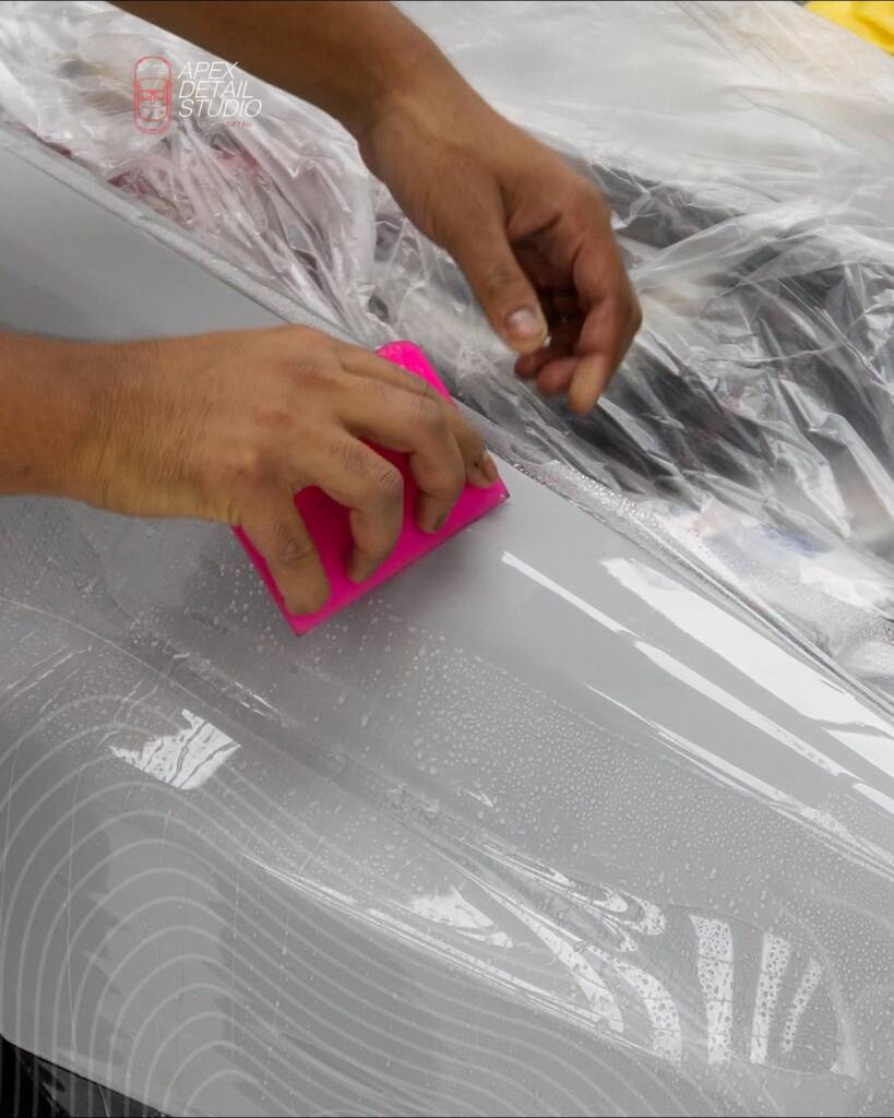 PPF being squeegeed onto a Nardo Grey panel of the Lancia Delta Integrale at Apex Detail Studio Dubai