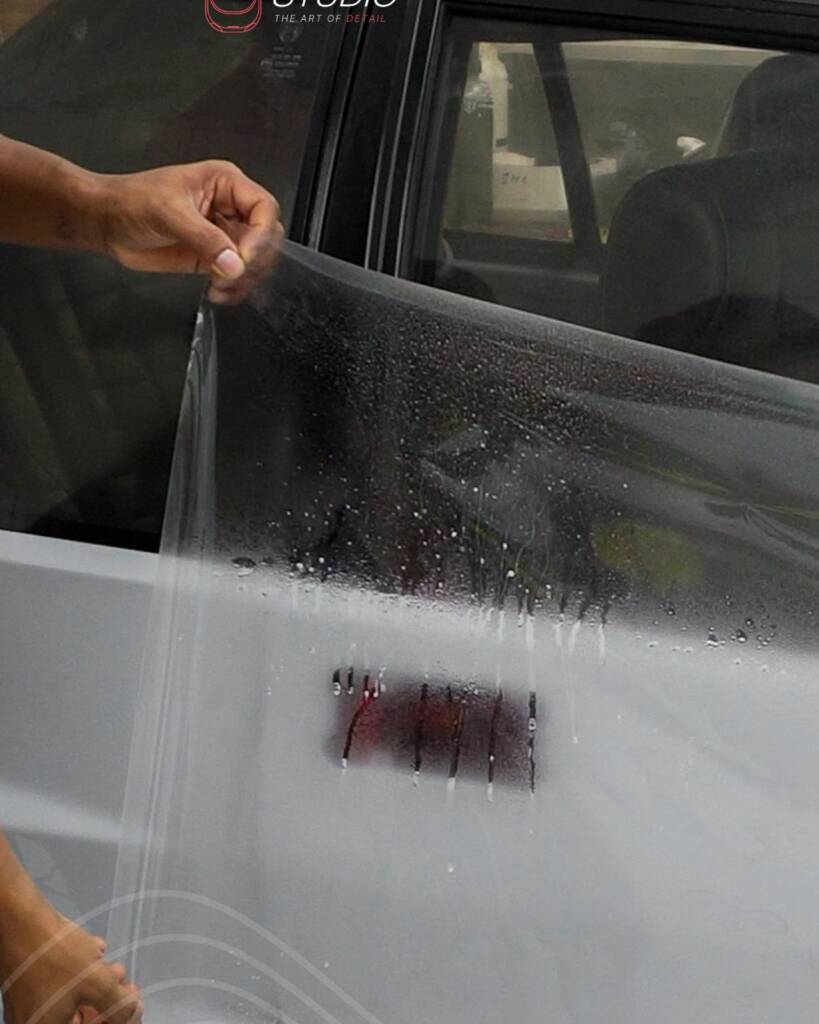 Installer lifting PPF along the door window line of the Lancia Delta Integrale at Apex Detail Studio Dubai