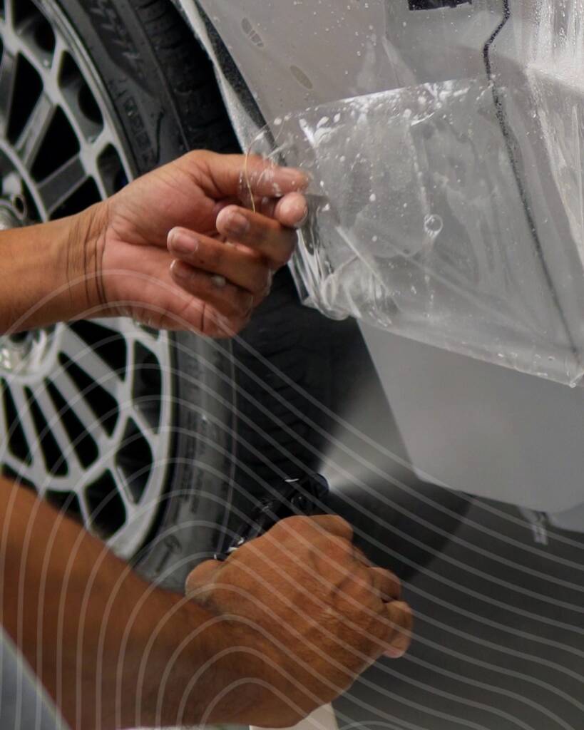 Installers stretching paint protection film around the rear arch of the Lancia Delta Integrale at Apex Detail Studio Dubai