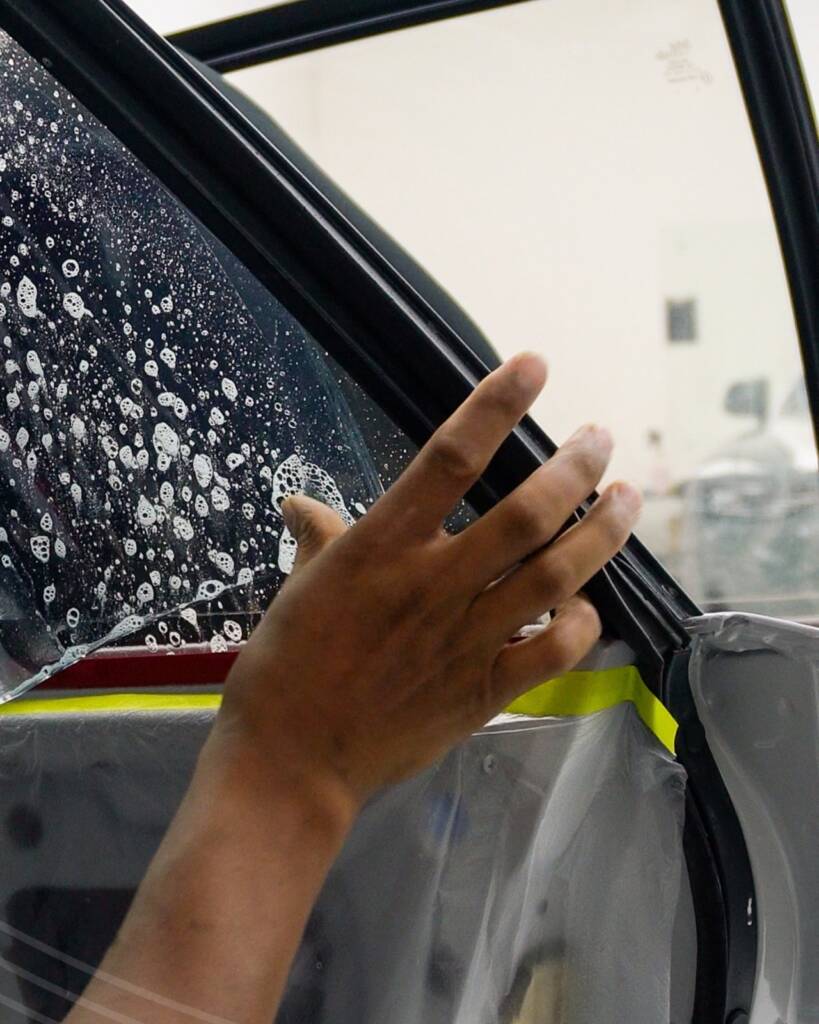 Window tint film being smoothed onto the Lancia Delta Integrale door glass at Apex Detail Studio Dubai