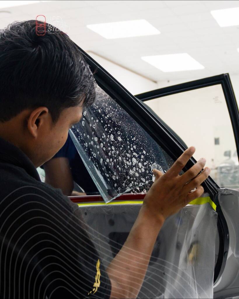 Installer fitting window tint film to the door glass of the Lancia Delta Integrale at Apex Detail Studio Dubai
