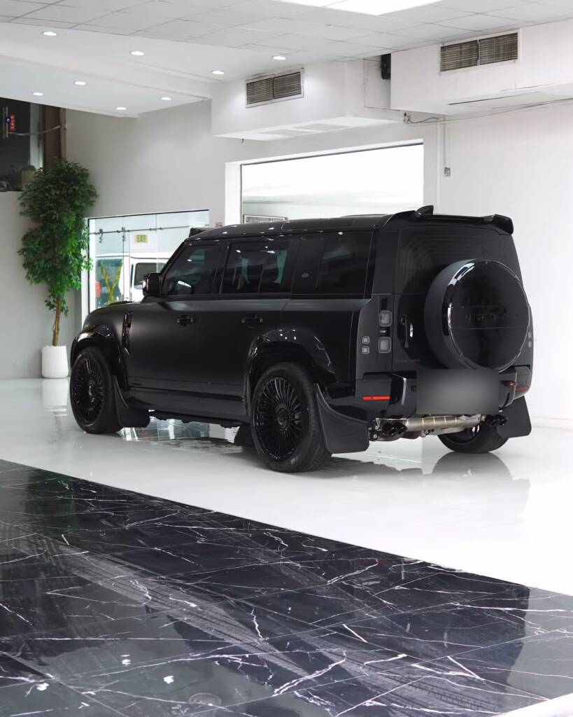 Finished 2026 Land Rover Defender with full body kit, rear three quarter in the Apex showroom