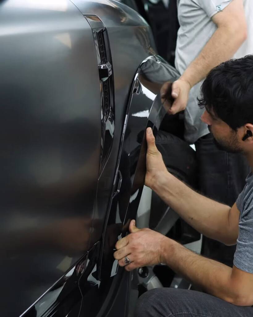 Two installers fitting a body kit arch on a 2026 Land Rover Defender, Apex Dubai