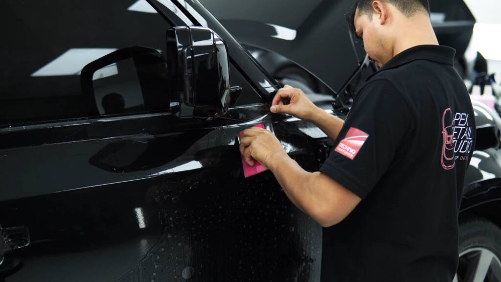 Installer fitting PPF to the door of a new Land Rover Defender, Dubai