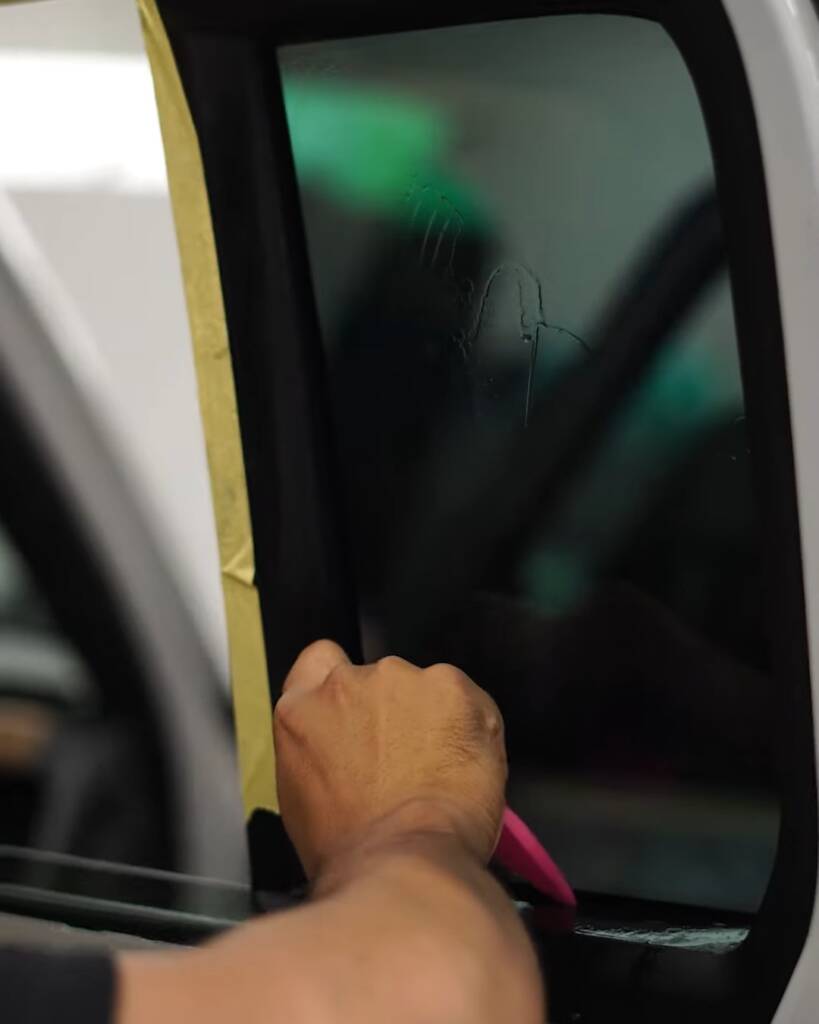 Finishing the tint edge at the door frame of a 2026 Land Rover Defender, Apex Dubai