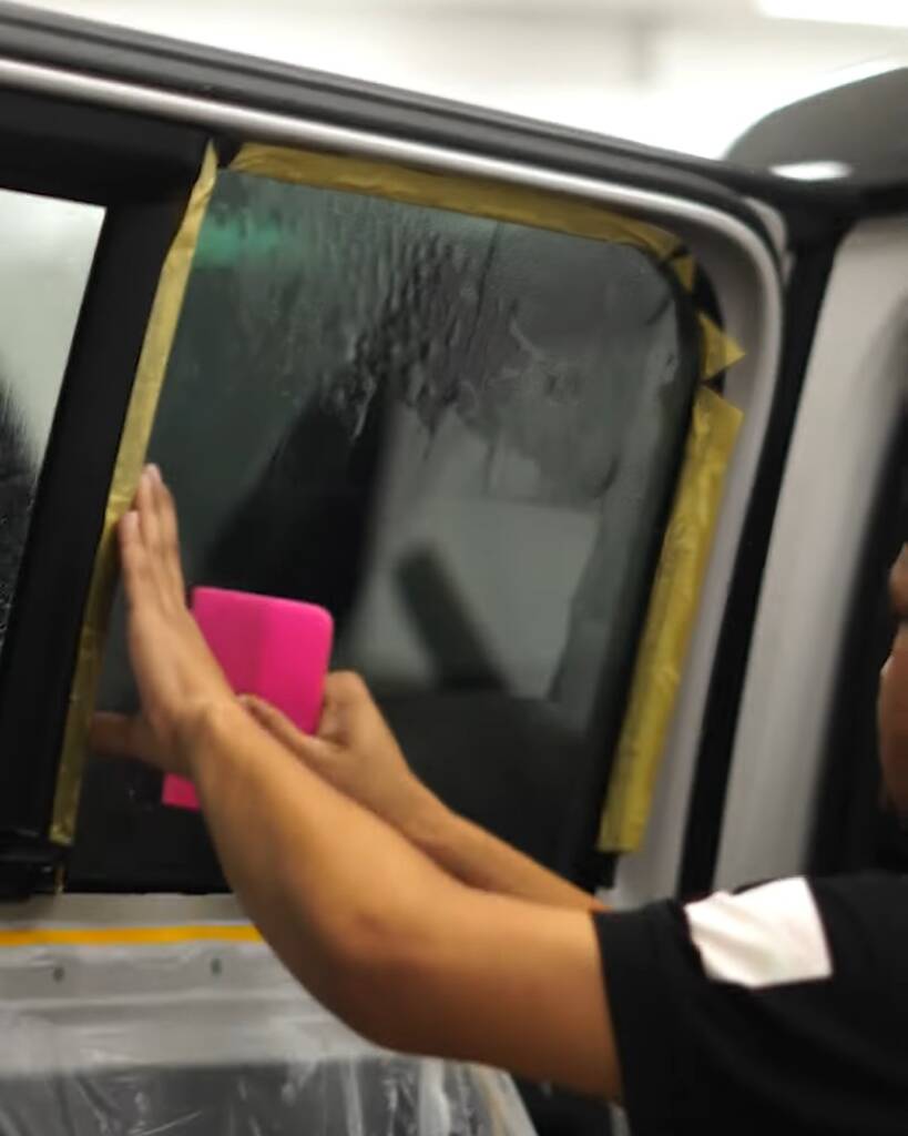 Window tint film laid on wet front door glass of a 2026 Land Rover Defender, Dubai