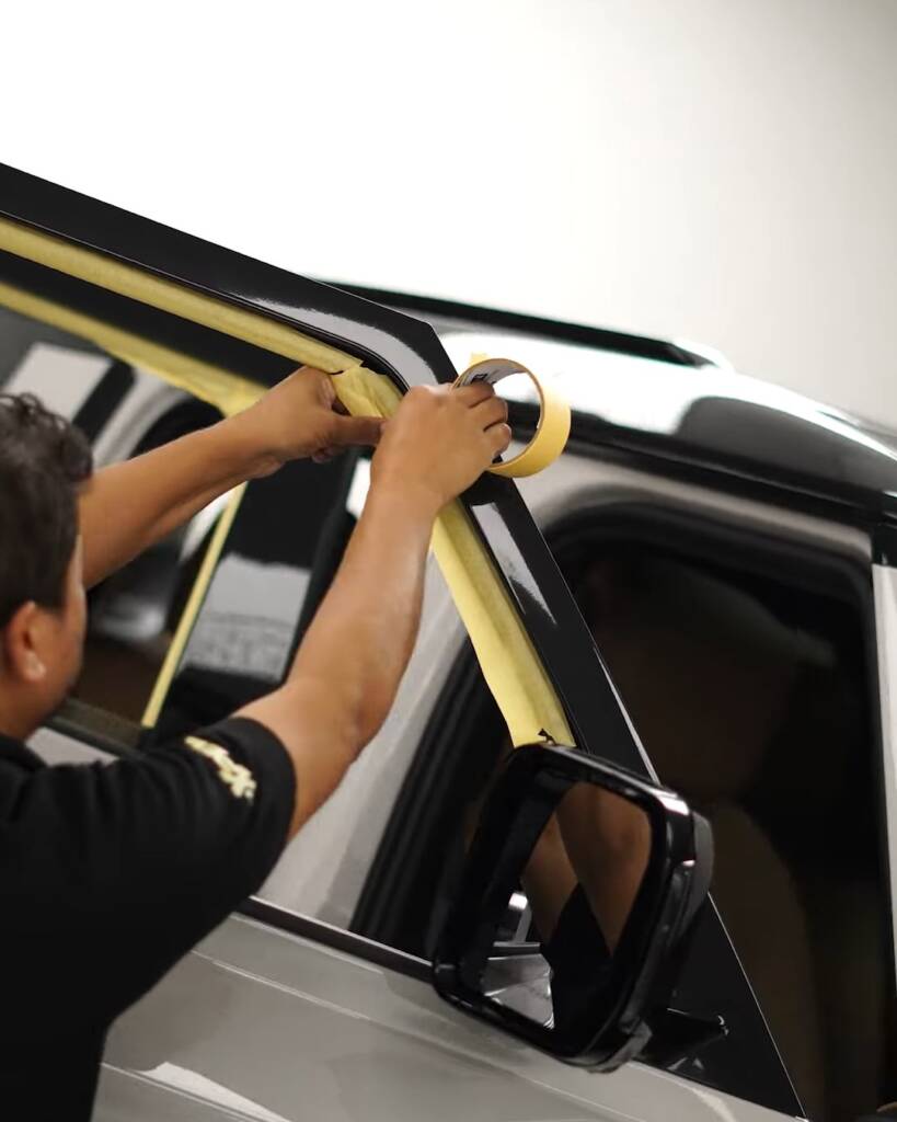 Installers masking the door frame of a 2026 Land Rover Defender before window tint, Dubai