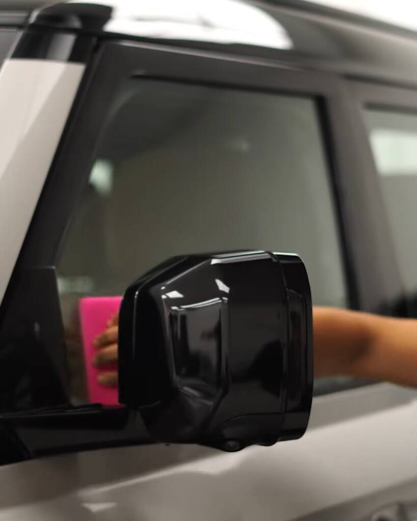 Squeegee on the front door glass of a 2026 Land Rover Defender during tint, Apex Dubai