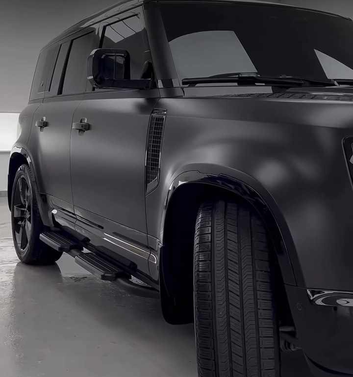 Side view of a blacked-out Land Rover Defender with black painted side steps at Apex Detail Studio Dubai