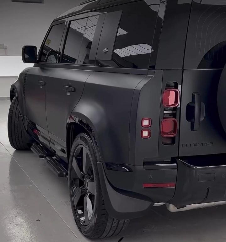Rear three-quarter view of a blacked-out Land Rover Defender with black painted wheels at Apex Detail Studio Dubai
