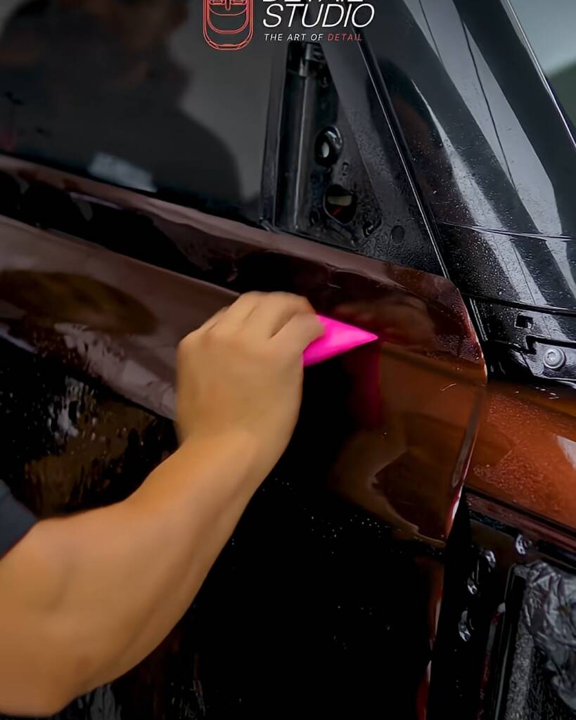 Pink squeegee on Sedona Red colour PPF on a Land Rover Defender lower panel